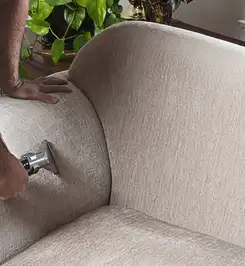 Professional upholstery cleaner deep-cleaning a fabric sofa with a handheld extraction tool and hose Cape Coral, FL.